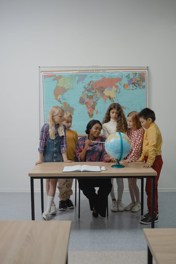 A teacher and students learning geography with a globe in the classroom.